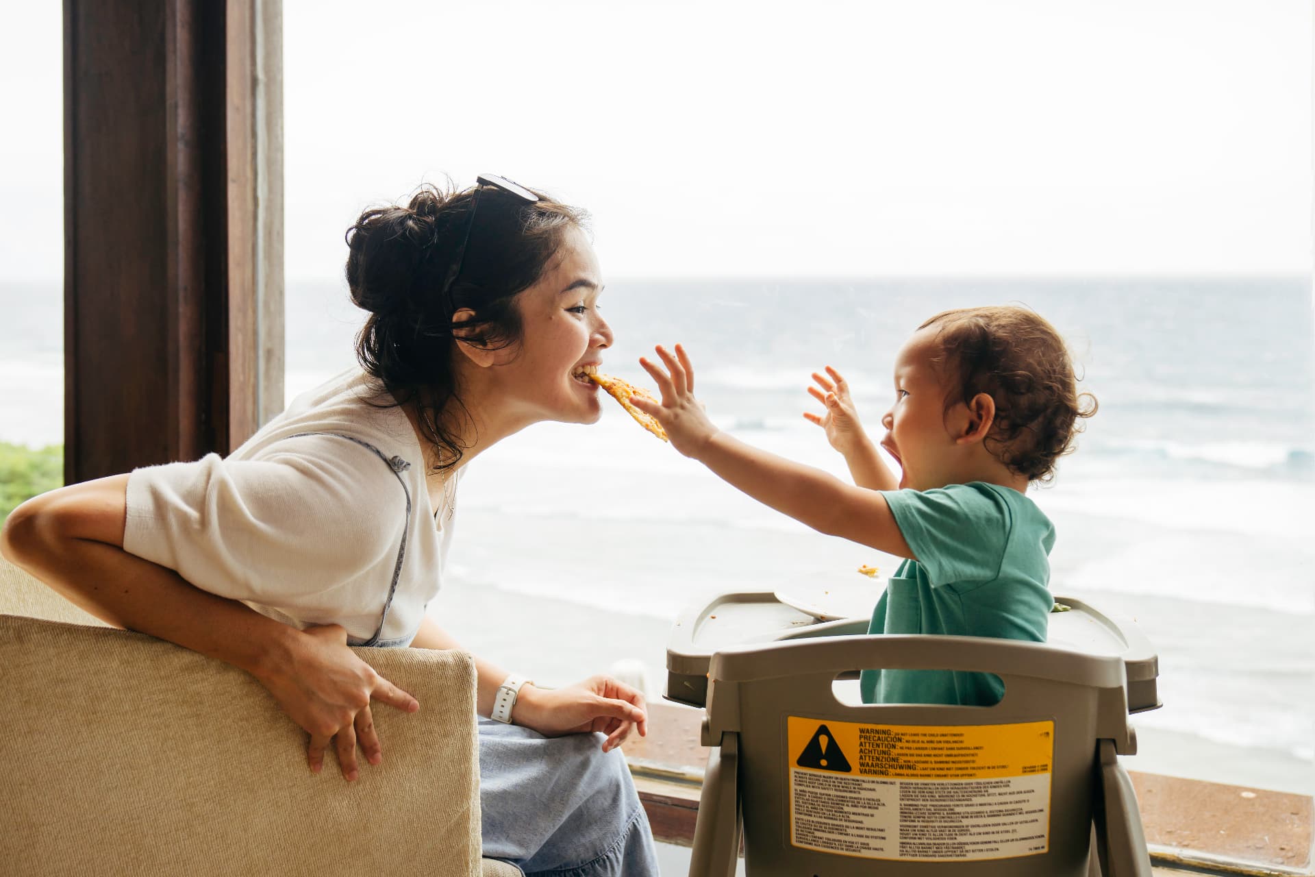 A mother and young child sharing a quiet moment at a café table while another family reads nearby